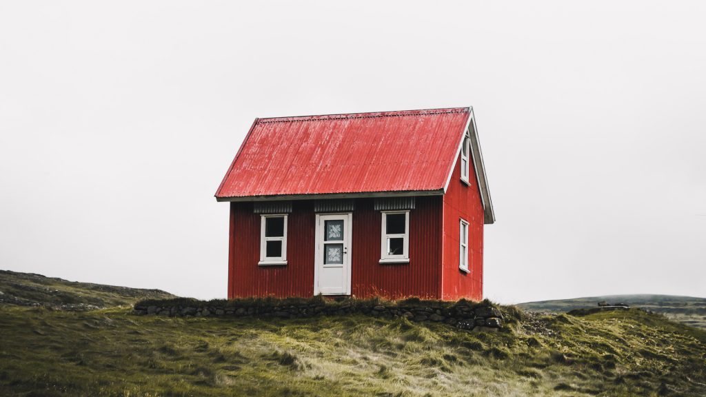 Red house on top of a hill. Photo by Photo by Luke Stackpoole on Unsplash